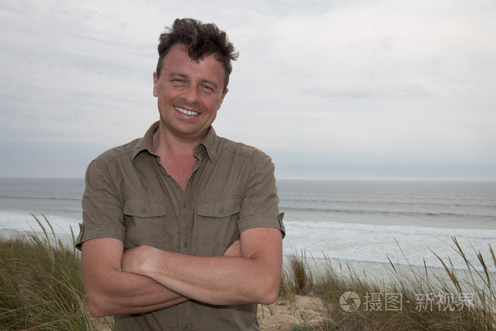 英俊的男人站在沙滩上若有所思地望著远方