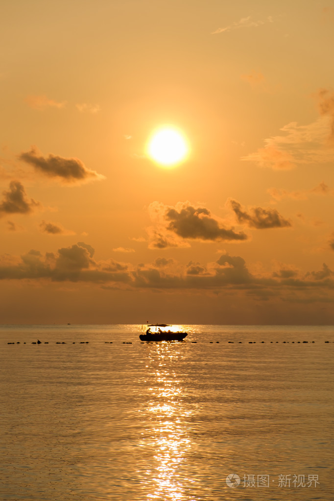 海上日出时用的小船的轮廓的海景