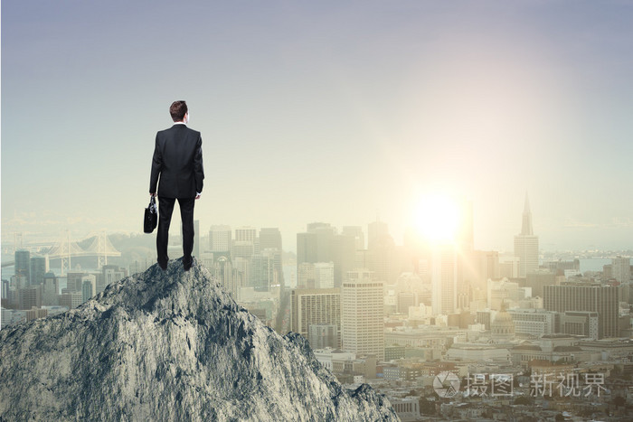 研究概念与商人站在山顶上和城市上空看着太阳落山