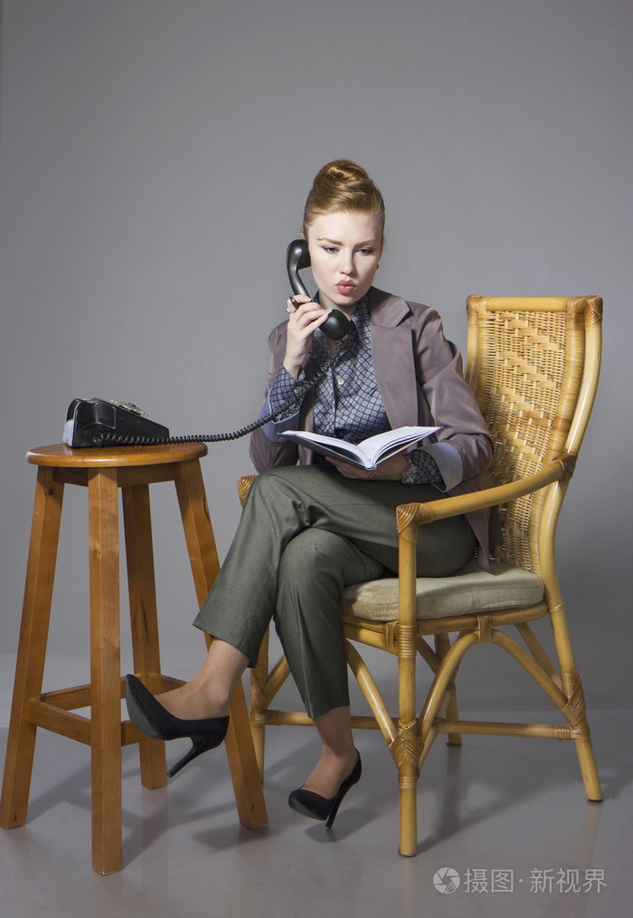 商务女性西装革履坐在椅子上,手里拿着一个笔记本,手里拿着一个软焦