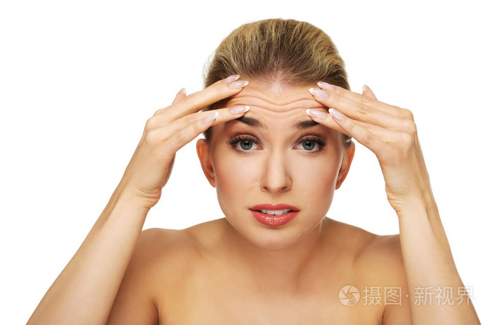 一个年轻的女人,检查她的额头上的皱纹