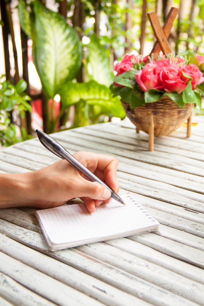 在笔记本上书写木桌上的女性手