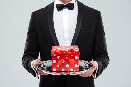 绅士管家在保持与礼品盒托盘的燕尾服的管家的特写照片