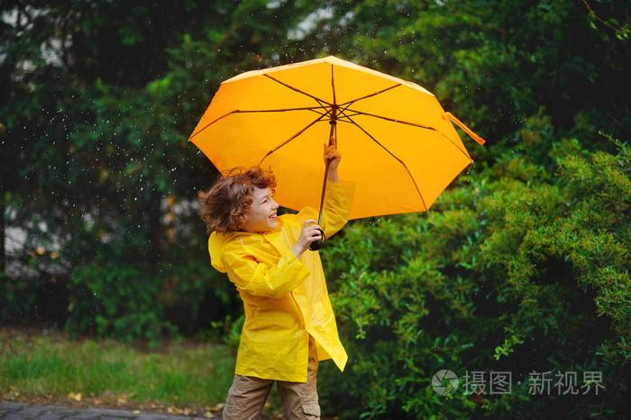89岁的男孩站在雨中用一把大黄色的雨伞