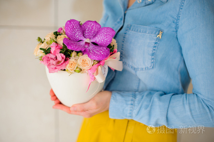 女孩抱着粉红色束美丽的混合鲜花插在花瓶里