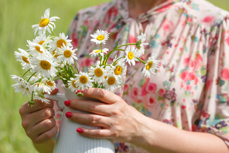 手拿花瓶女人手拿新鲜野雏菊束插在花瓶里照片