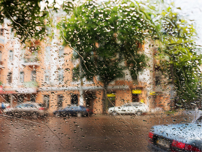 滴的雨水蓝色玻璃背景街头的散景灯熄灭