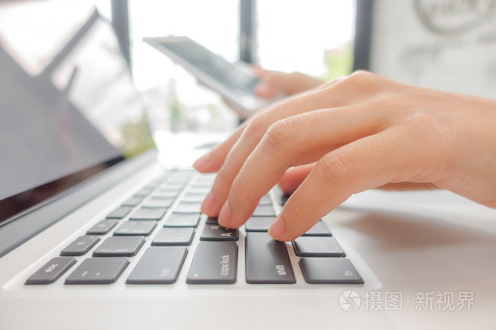 与mo 的笔记本电脑键盘上打字的商务女人手的特写