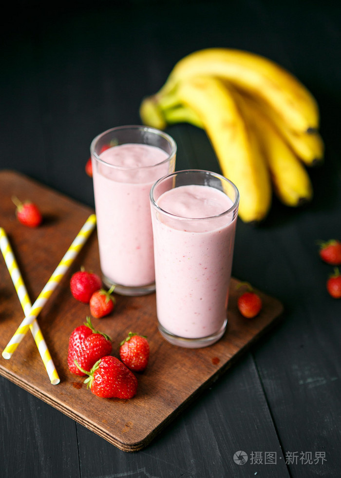 香蕉和草莓冰沙在黑色背景上的玻璃