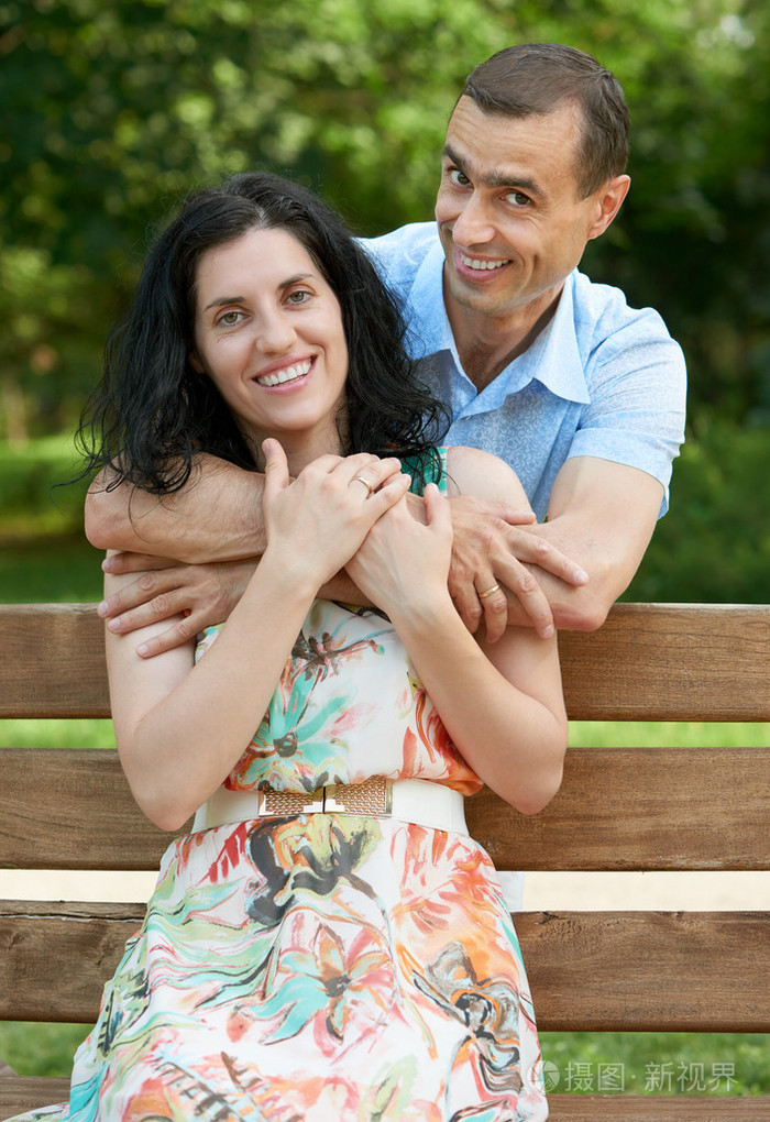 浪漫的情侣坐在长凳上的城市公园,盛夏季节,成人快乐的人男人和女人