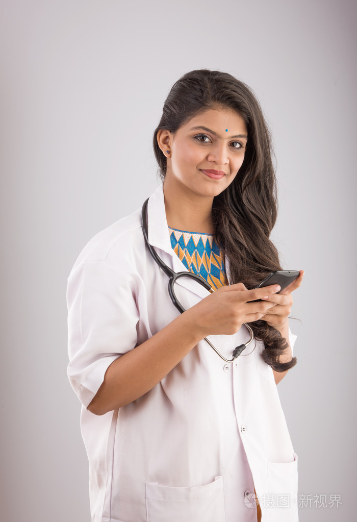 印度女医生与智能手机亚洲医生使用智能手机灰色的背景上孤立