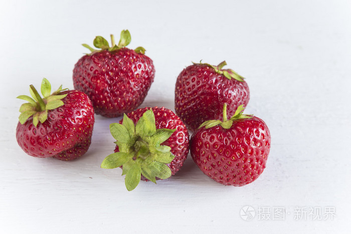 白色的木制背景上的五个草莓