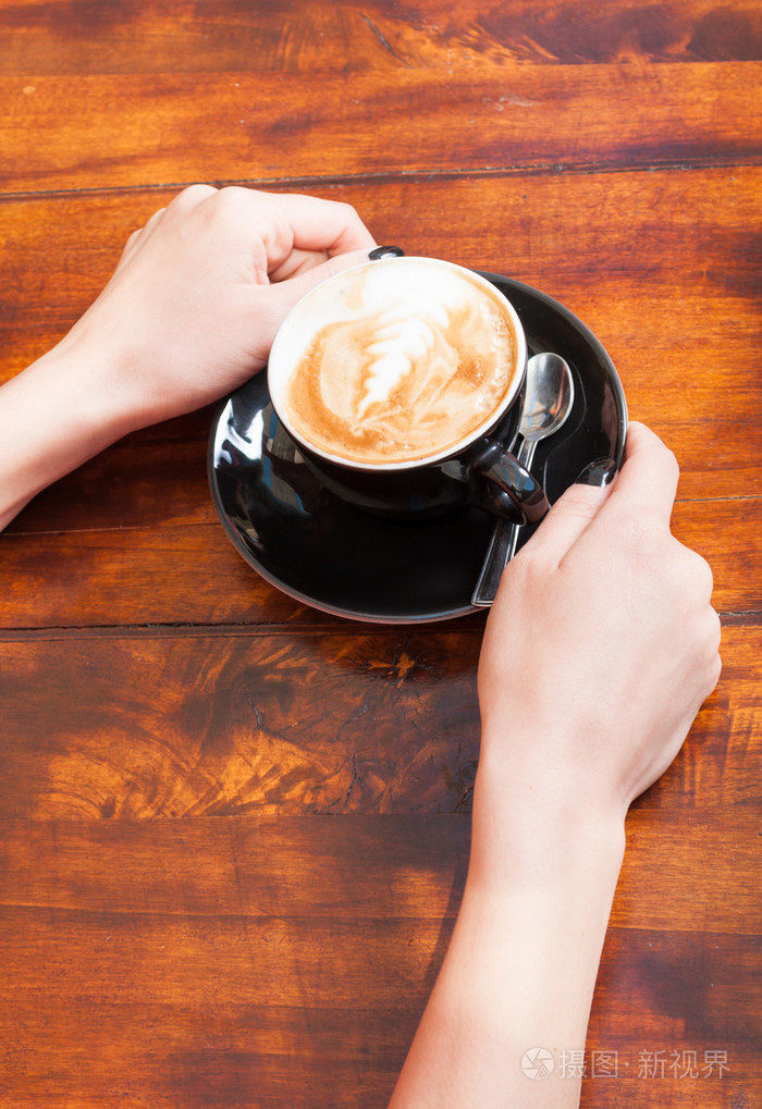 女人手里拿着咖啡木制的桌子上