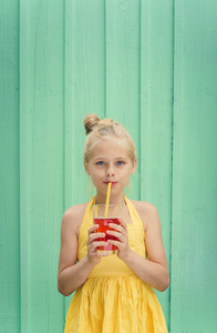 可爱的金发女孩喝红柠檬水图片