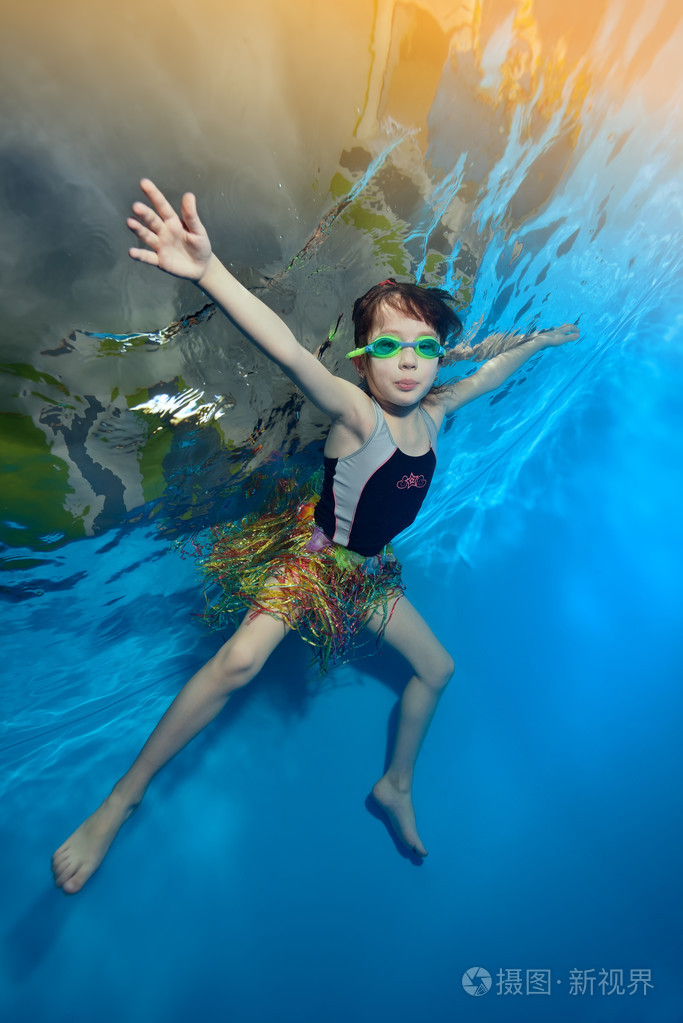 快乐的小女孩游泳和打水下在蓝色背景上的池肖像底视图垂直方向