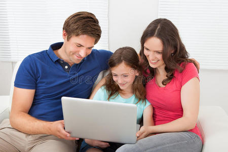 在沙发上使用笔记本电脑的家庭