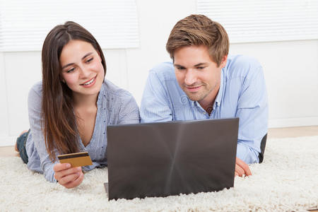 夫妇使用笔记本电脑和信用卡在线购物