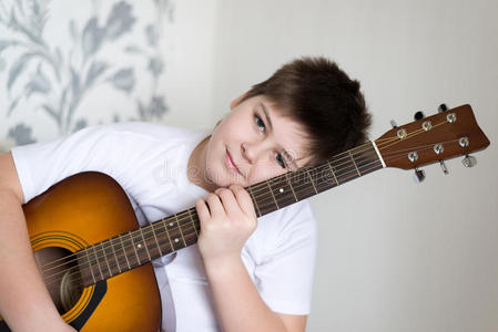 一个十几岁的男孩弹一把原声吉他
