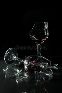 破碎的杯子，反射在玻璃桌子上，隔离在黑色上