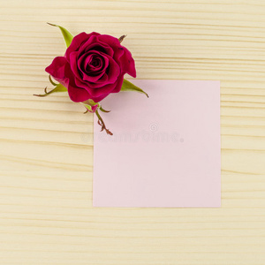 木制背景上的空白粉红色纸和玫瑰花
