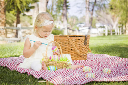 可爱的女婴在野餐毯上给复活节彩蛋着色