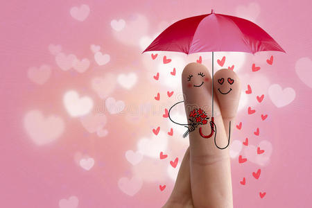 概念手指艺术。 恋人们拥抱着，拿着雨伞，心在坠落。 股票形象