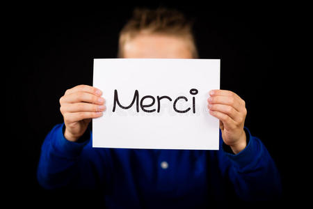 孩子拿着法语单词Merci的标志谢谢