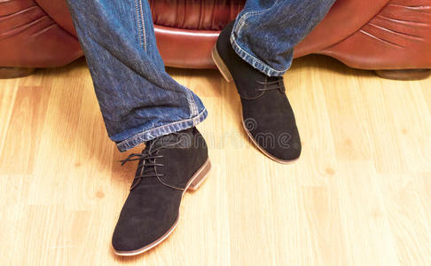 穿着牛仔裤和鞋子在皮革沙发上的男人