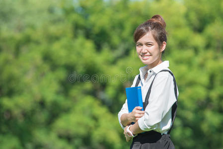 户外女学生拿着笔记本微笑着