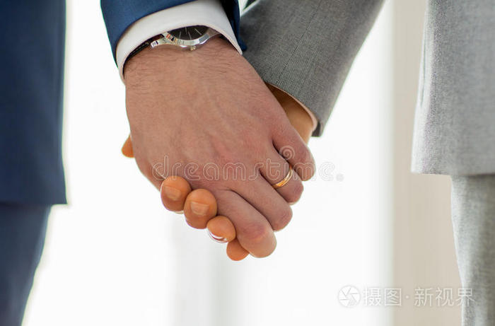 亲密的男同性恋夫妇戴着结婚戒指幸福男同性恋情侣牵手特写把一对戴着
