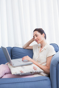 休闲黑发女人在沙发上使用笔记本电脑