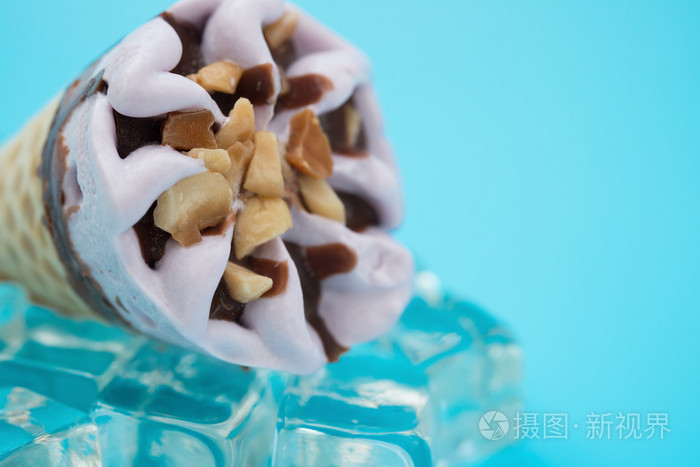 花生的风味冰淇淋甜筒在冰块上紧靠蓝色背景