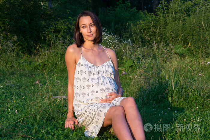 怀孕的女孩坐在草地上