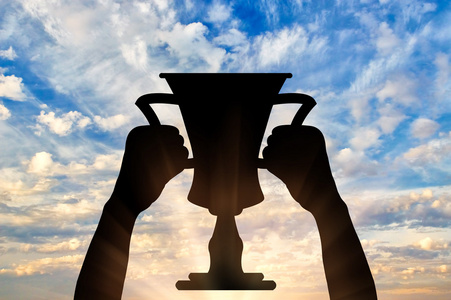手举冠军奖杯一只手握着冠军奖杯的剪影照片