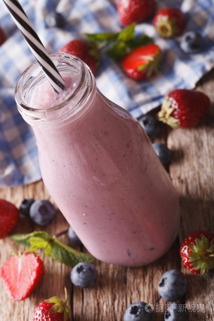 牛奶冰沙与草莓和蓝莓在玻璃瓶