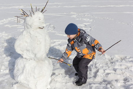 小男孩在建设一个雪人颜色夹克图片
