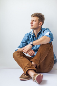 严重的帅哥坐在地板上照片