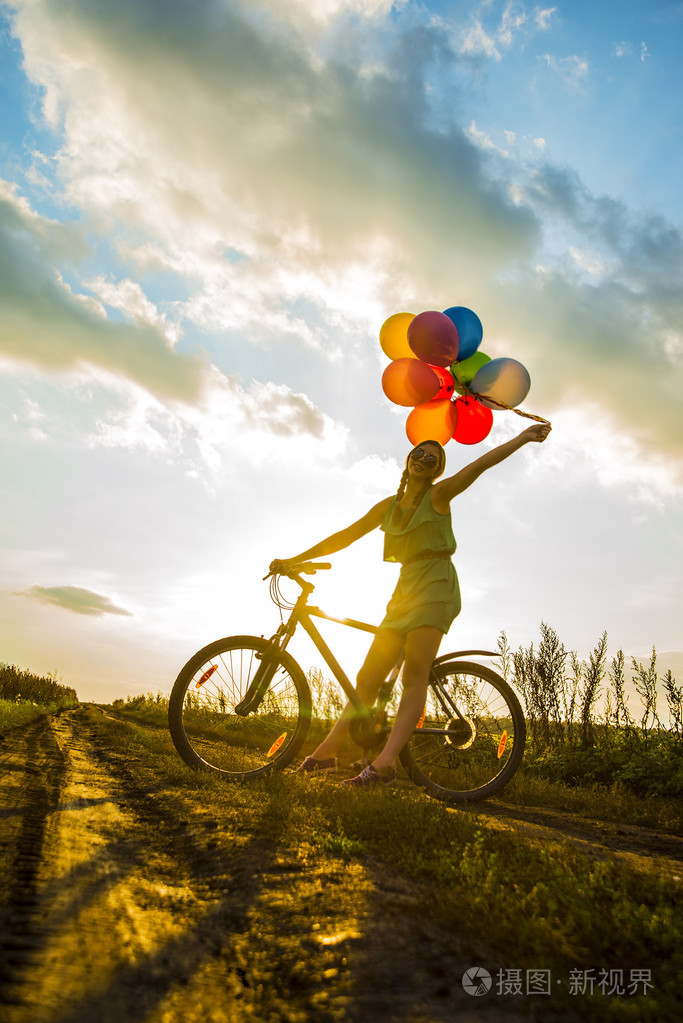 穿着性感裙子骑自行车飞气球的少女