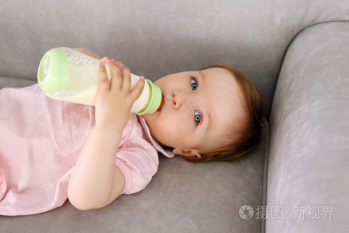 在沙发上喝牛奶的婴儿