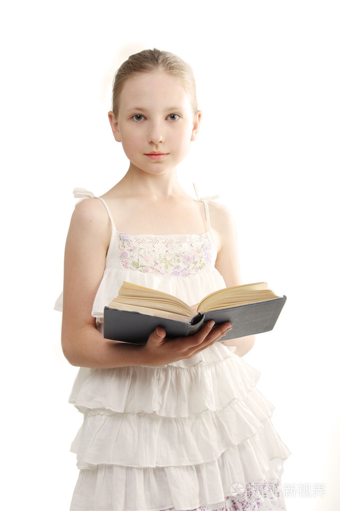 十几岁的女孩穿上白色的裙子和白色背景上她手里拿着一本打开的书的