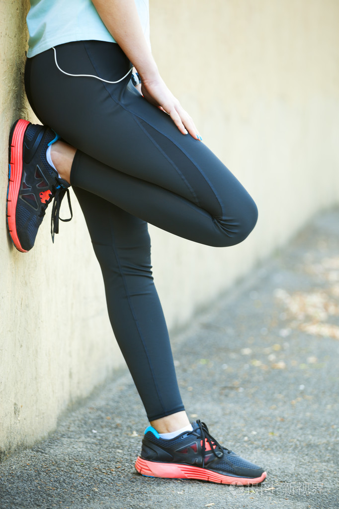 女子赛跑运动员握住她的手上受伤的腿