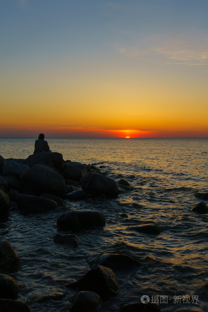 男子坐在海边的石头