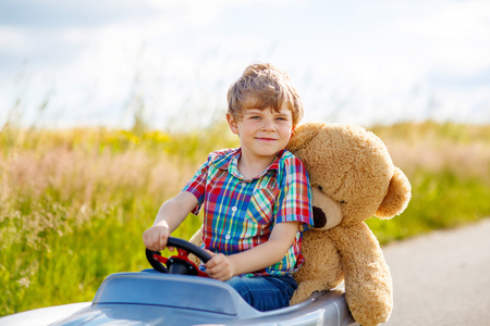 户外开车开车的大玩具和一只熊,在户外的小小孩男孩照片