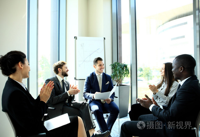 群五个年轻人坐在办公室中的表在一起讨论的东西