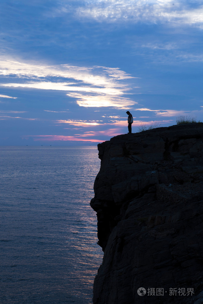 伤心的人在悬崖上的剪影