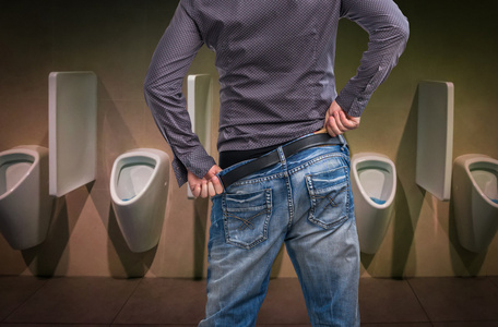 男人在洗手间小便小便站到小便池在厕所里的人公共卫生间白色陶瓷小便
