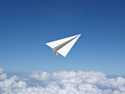 纸飞机在云层之上的蓝天下穿着宇航员服装的小女孩正在玩耍,梦想成为