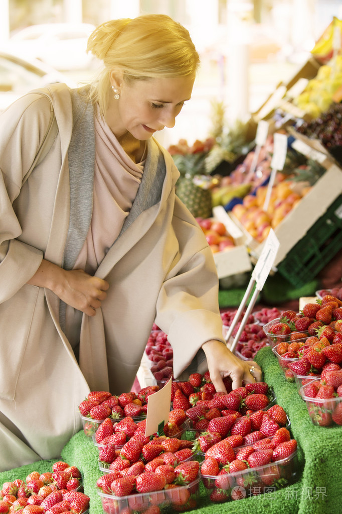女人站在看着草莓水果摊