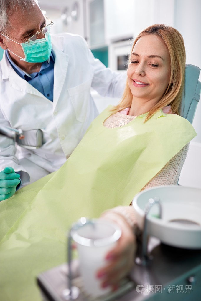 女性患者在牙科椅带杯水
