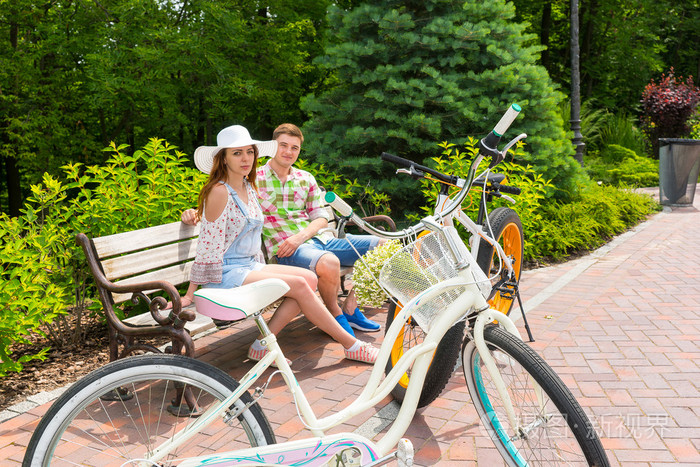 年轻男性和女性坐在长椅上附近自行车